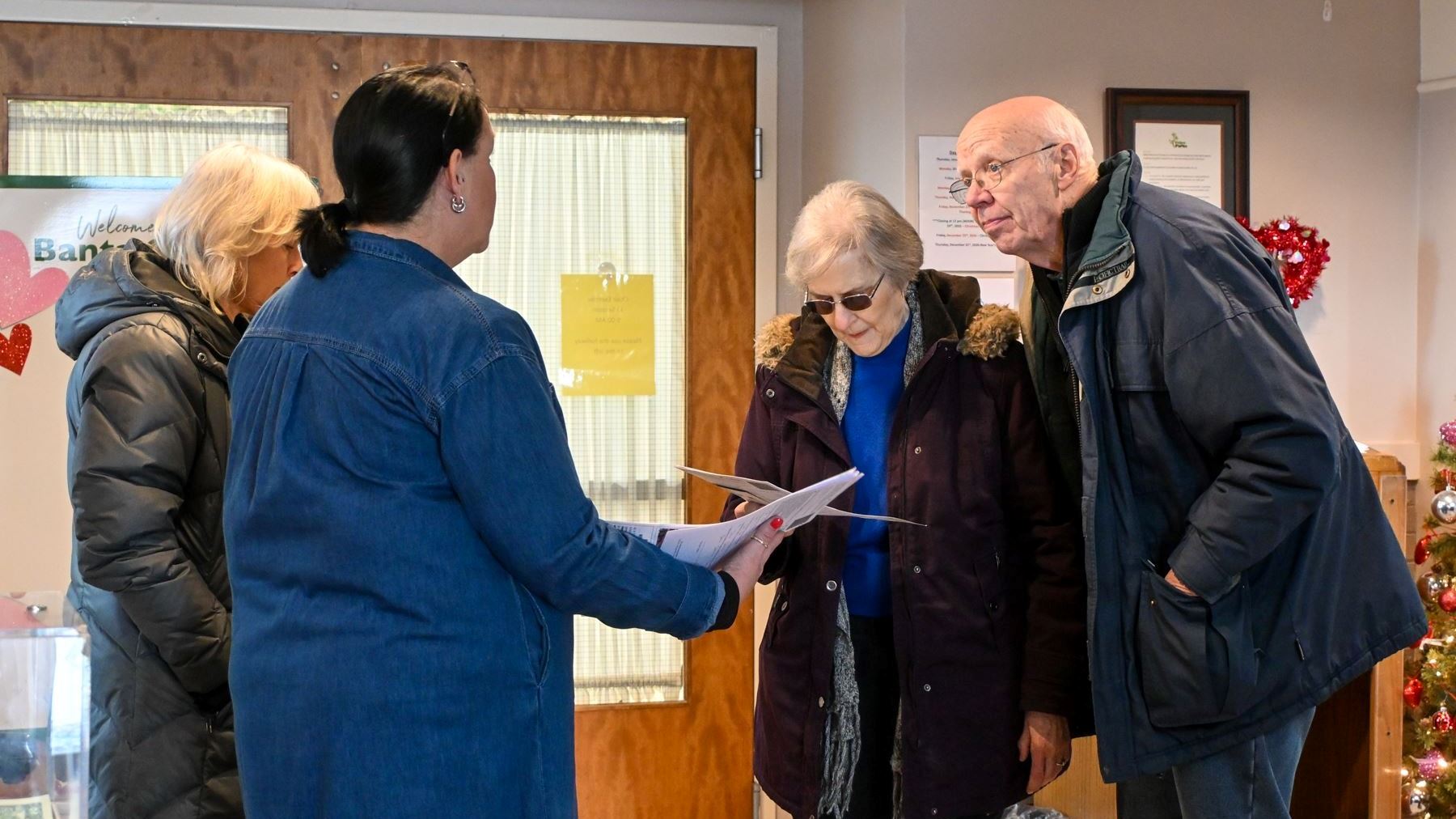 A woman passing papers to a senior couple