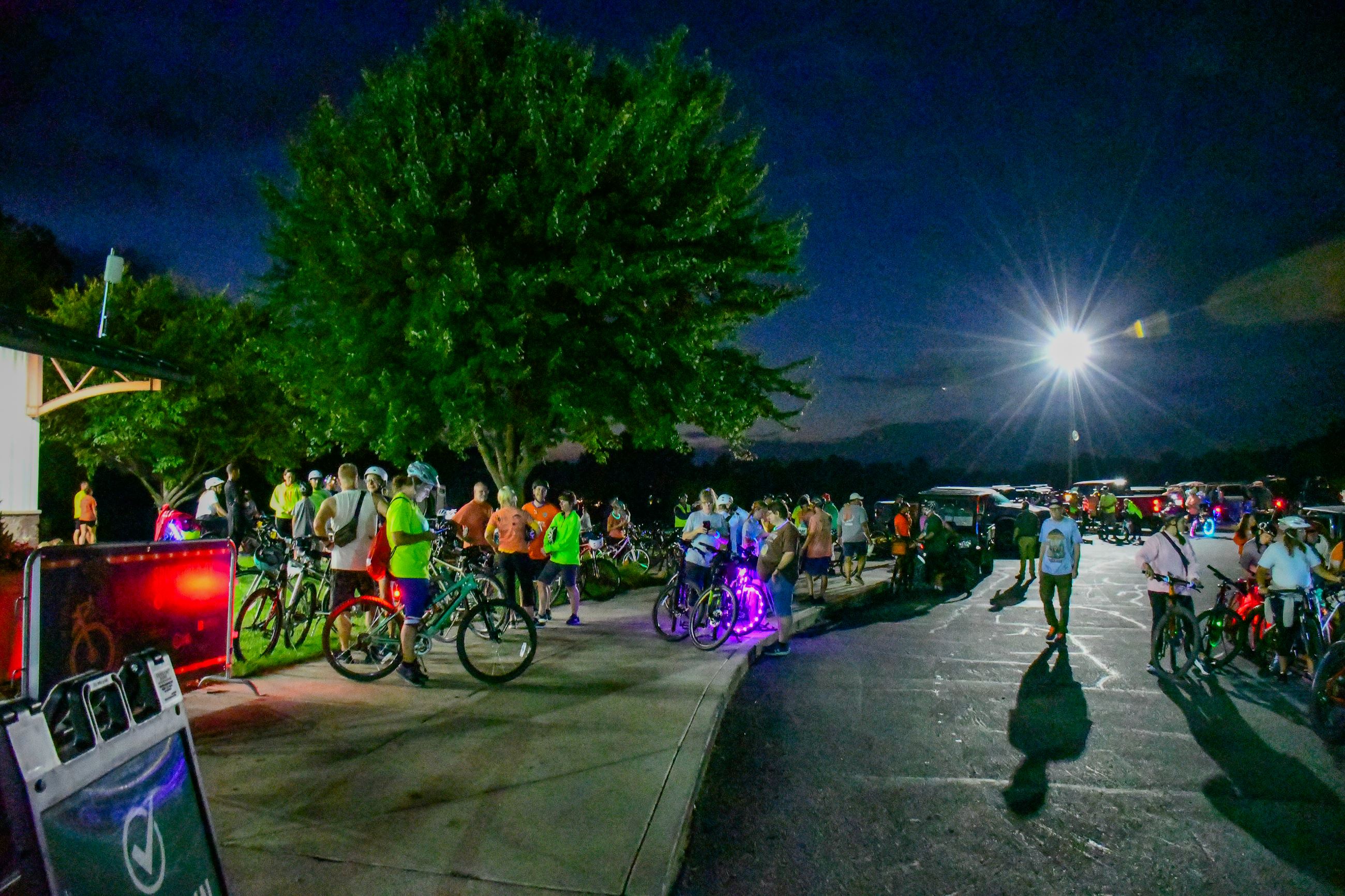 A crowd of cyclists at night, some with lights