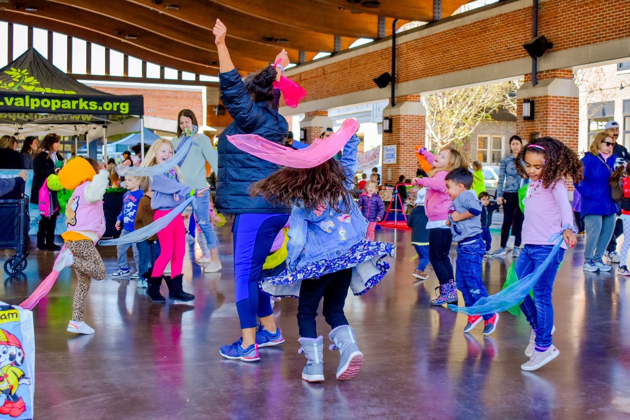 Kids and an adult dancing with scarves in a pavilion